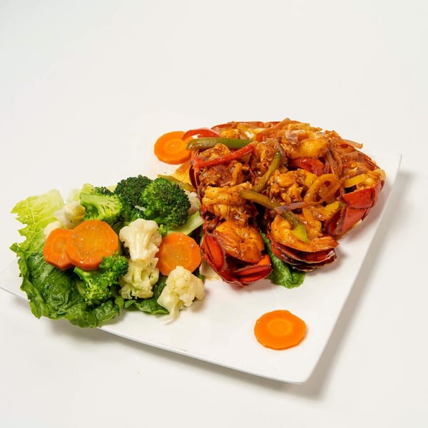 Lobster tail with mixed vegetables including broccoli, cauliflower, and carrots on a white plate.