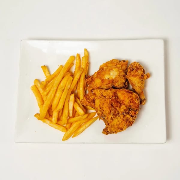 Crispy fried chicken pieces and golden french fries served on a white rectangular plate.