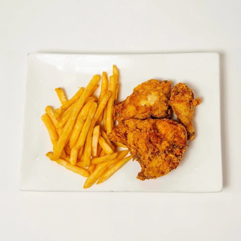 Crispy fried chicken pieces and golden french fries served on a white rectangular plate.