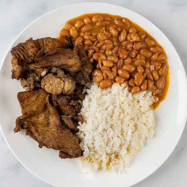 Pollo Lounge and Grill's grilled chicken, rice, and beans on a white plate.